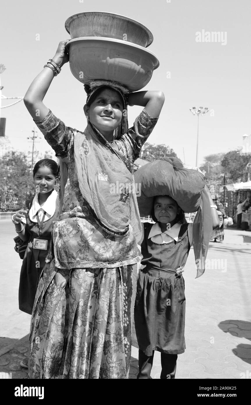 Patan: Indian woman with her two daughters carring water bowls on her head Stock Photo