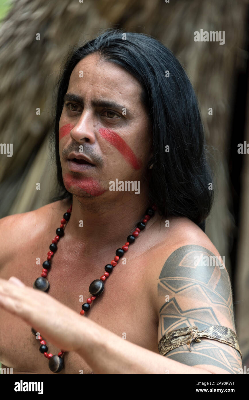 A member of the Taino-Arawak people, beating his drum and singing with others for visiting tourists visiting the Cueva del Indio, a cave, first discov Stock Photo
