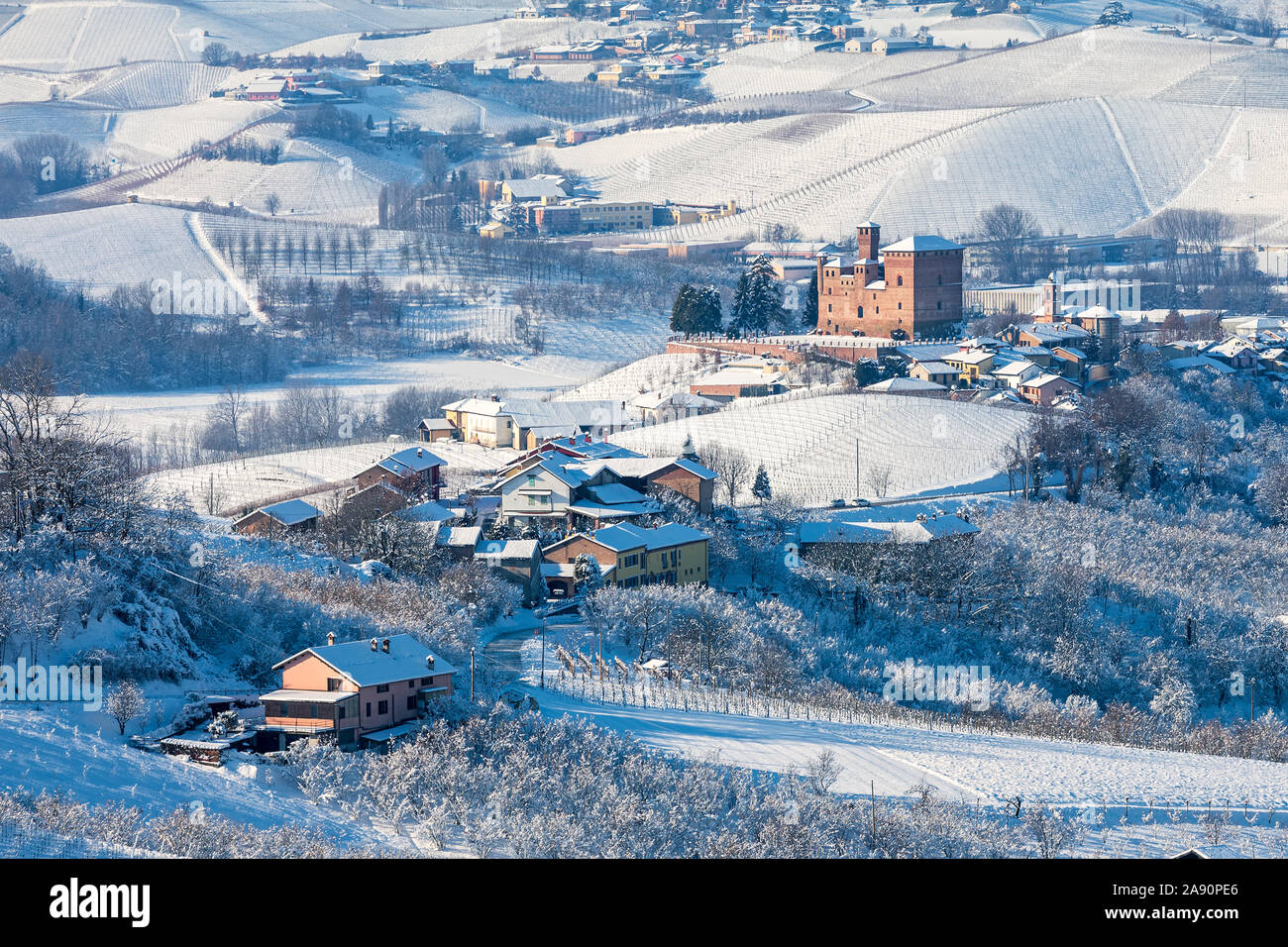 View of rural houses ans small medieval town of Grinzane Cavour on background on the hills covered in snow in Piedmont, Northern Italy. Stock Photo