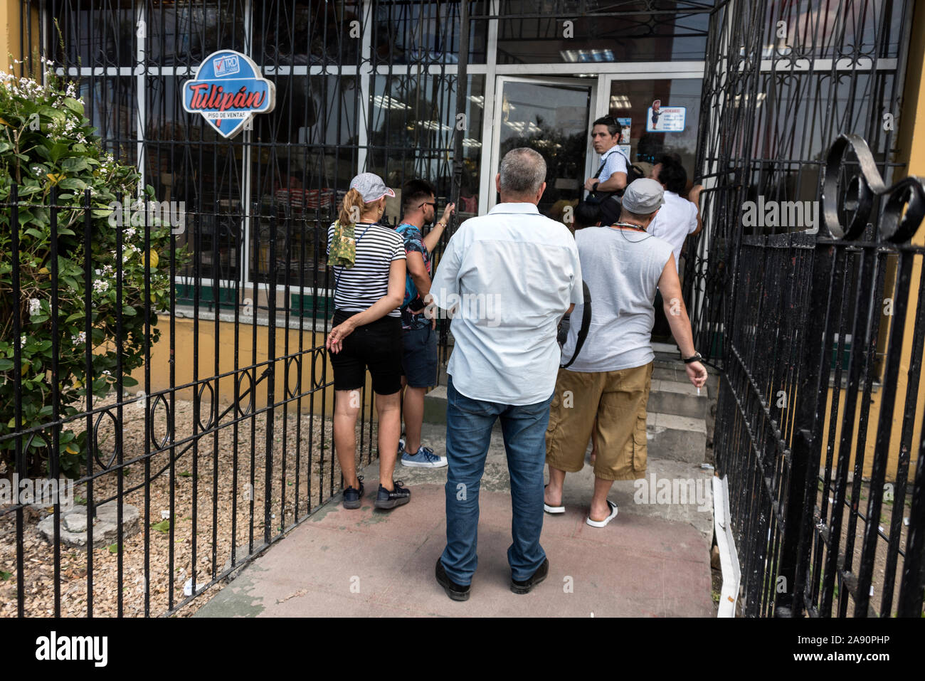 A queue formed outside a food shop as food is being rationed  in Havana, Cuba.   Due to food shortages, locals use their ration books to purchase food Stock Photo
