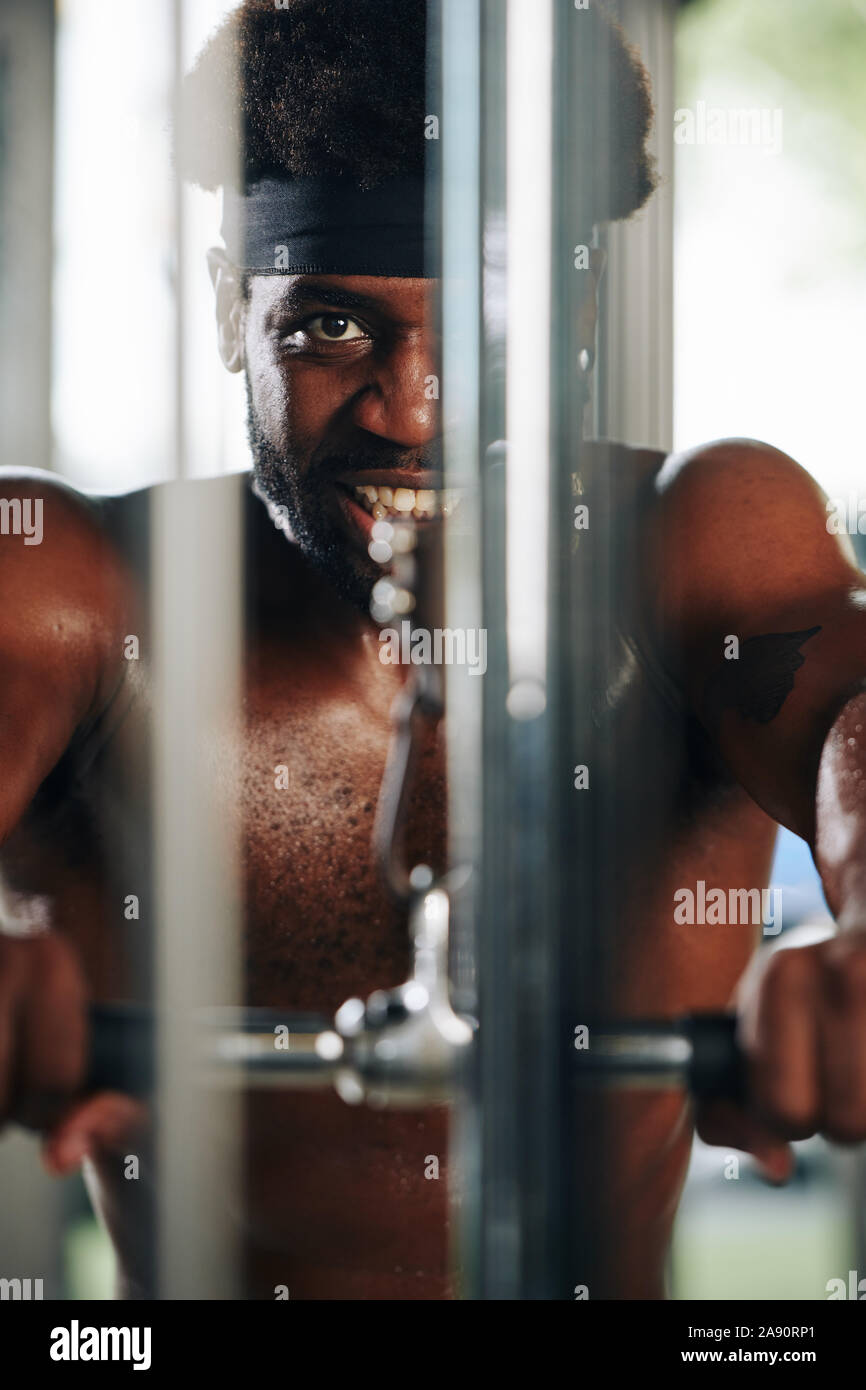 Smiling fit Black man doing exercises with pulldown machine in gym Stock Photo