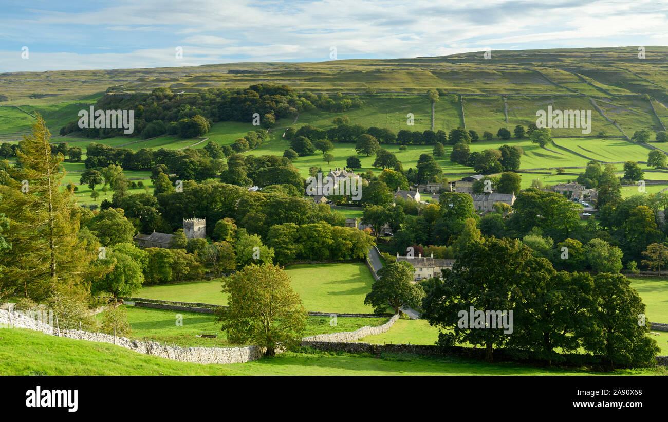Summer evening sunlight on picturesque Dales village (church & houses) nestling in valley under upland hills - Arncliffe, North Yorkshire, England, UK Stock Photo