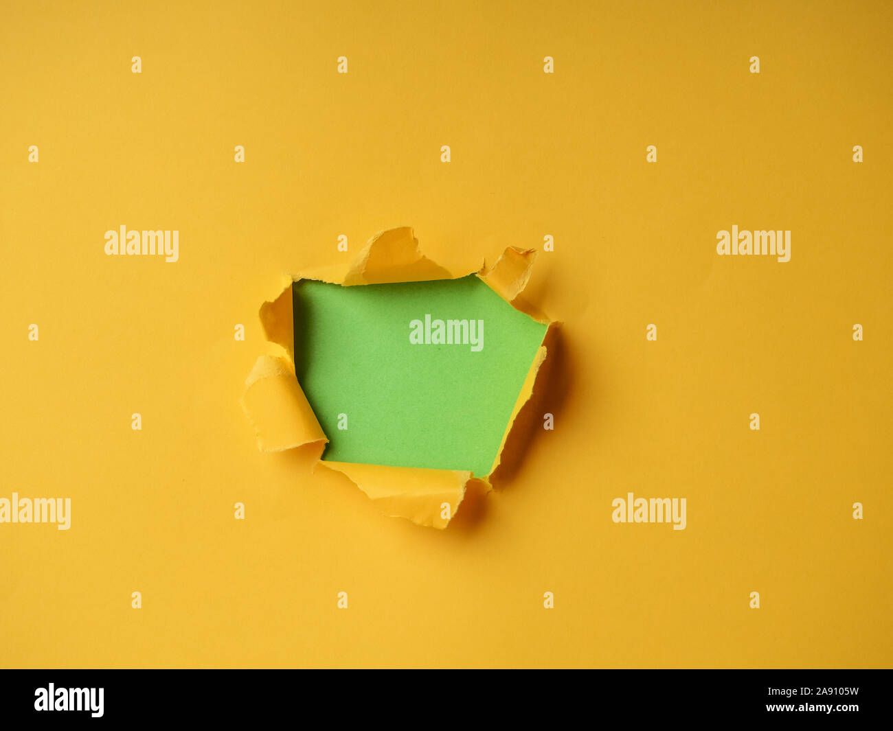 Small paper hole with torn sides over yellow background for your text