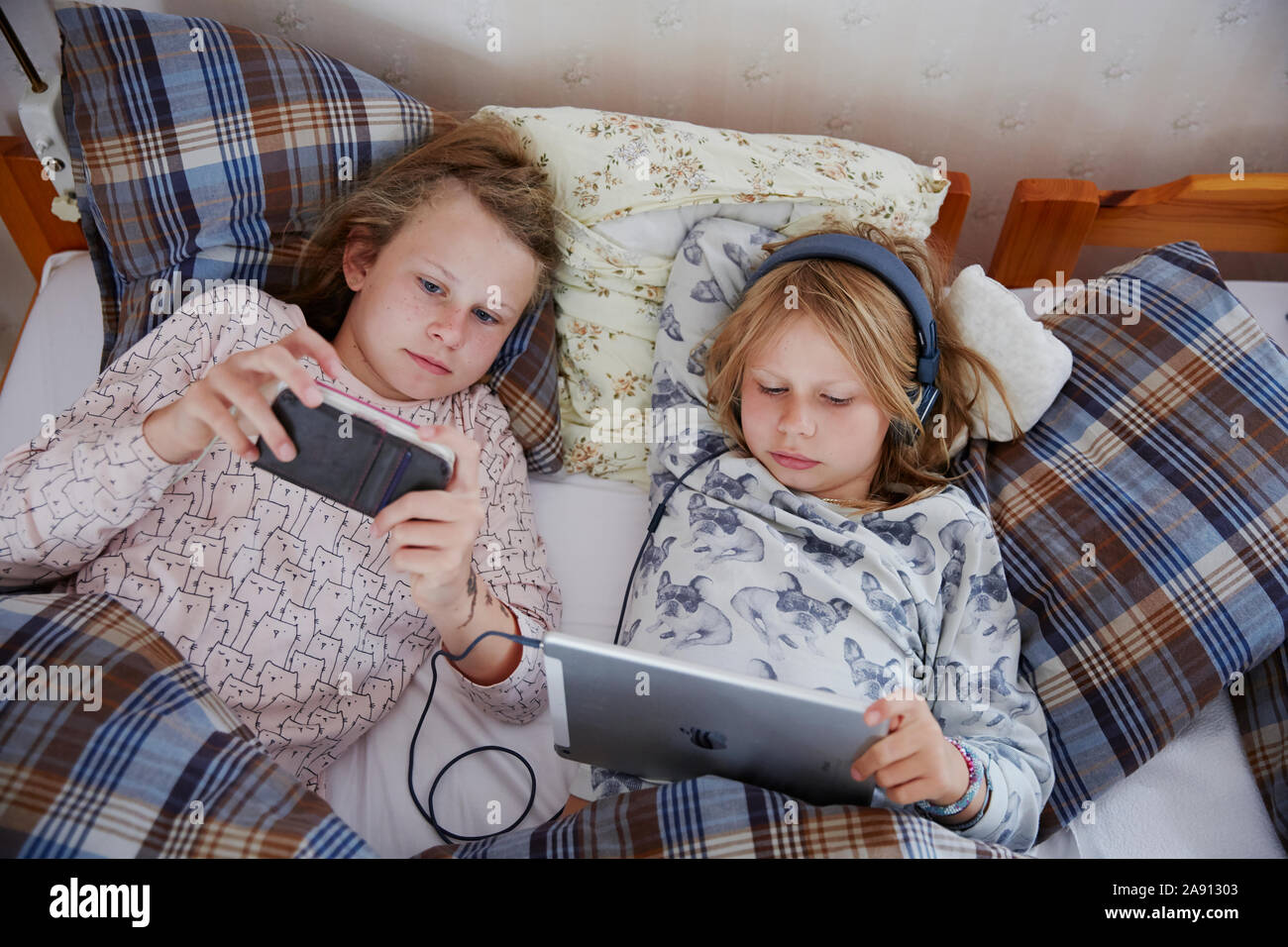 Sisters on bed using digital devices Stock Photo
