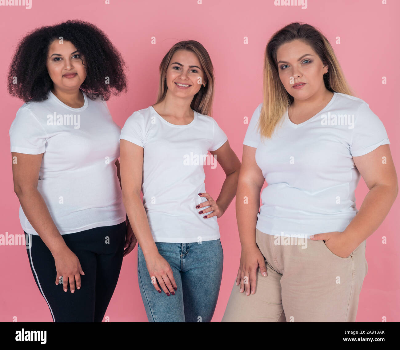 A group of girls in clean white t-shirts on a pink background. T-shirt mock-up for design on clothes Stock Photo