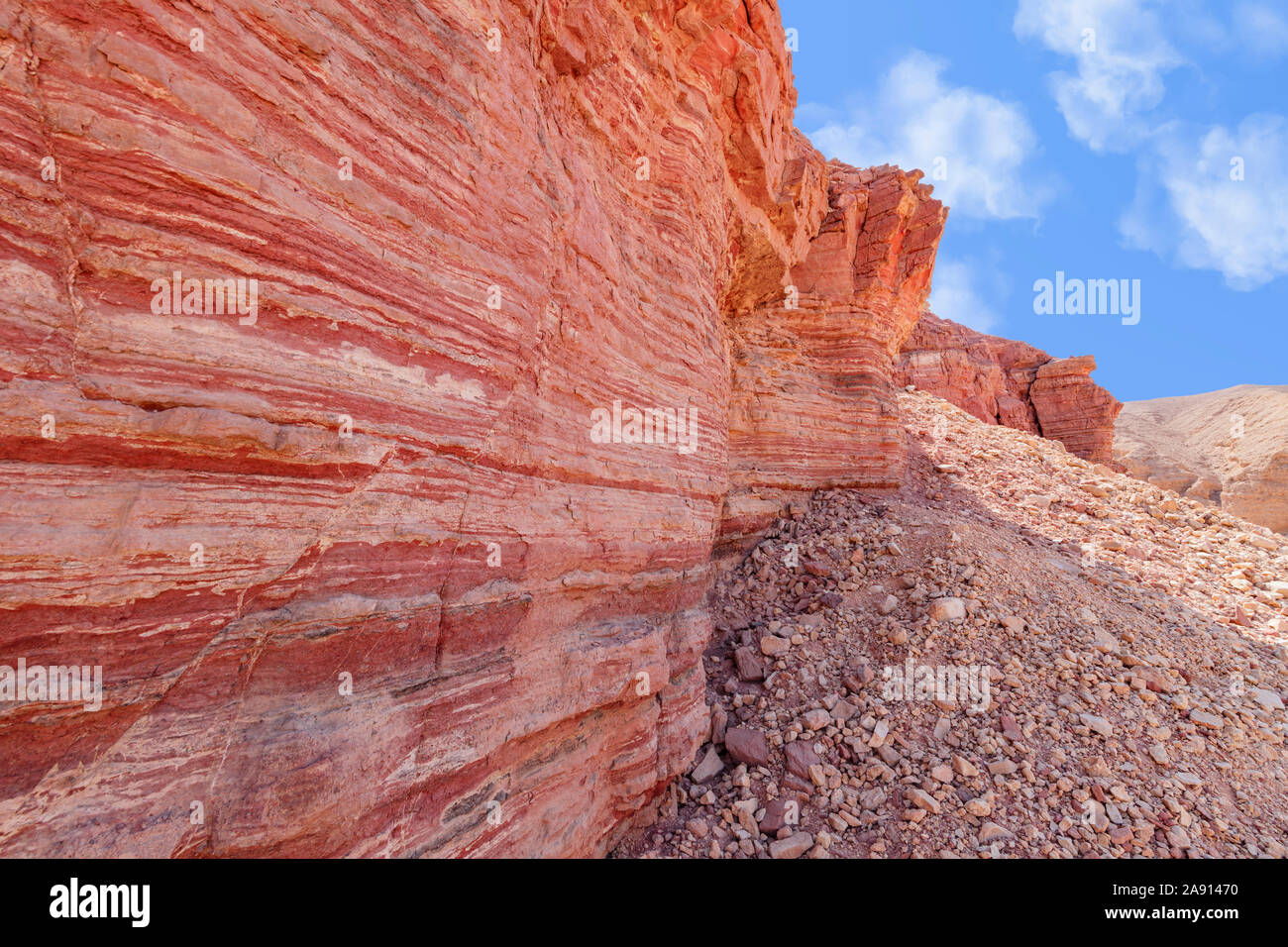 The surface of a crumbling hill with multicolored layers of rock. Red
