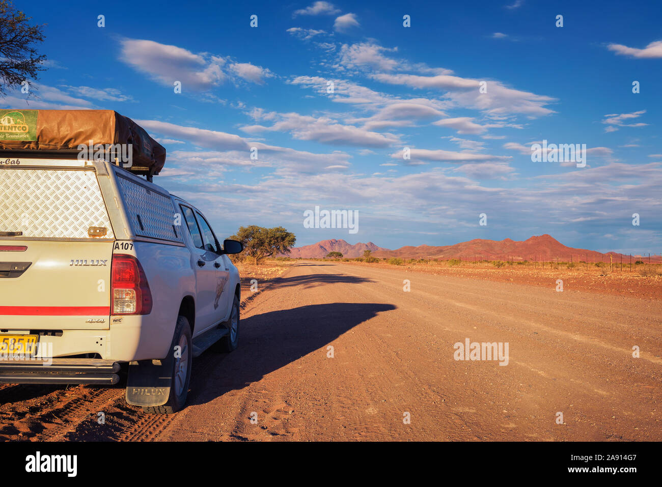 4x4 rental car equipped with a roof tent parks on a dirt road in Namibia Stock Photo