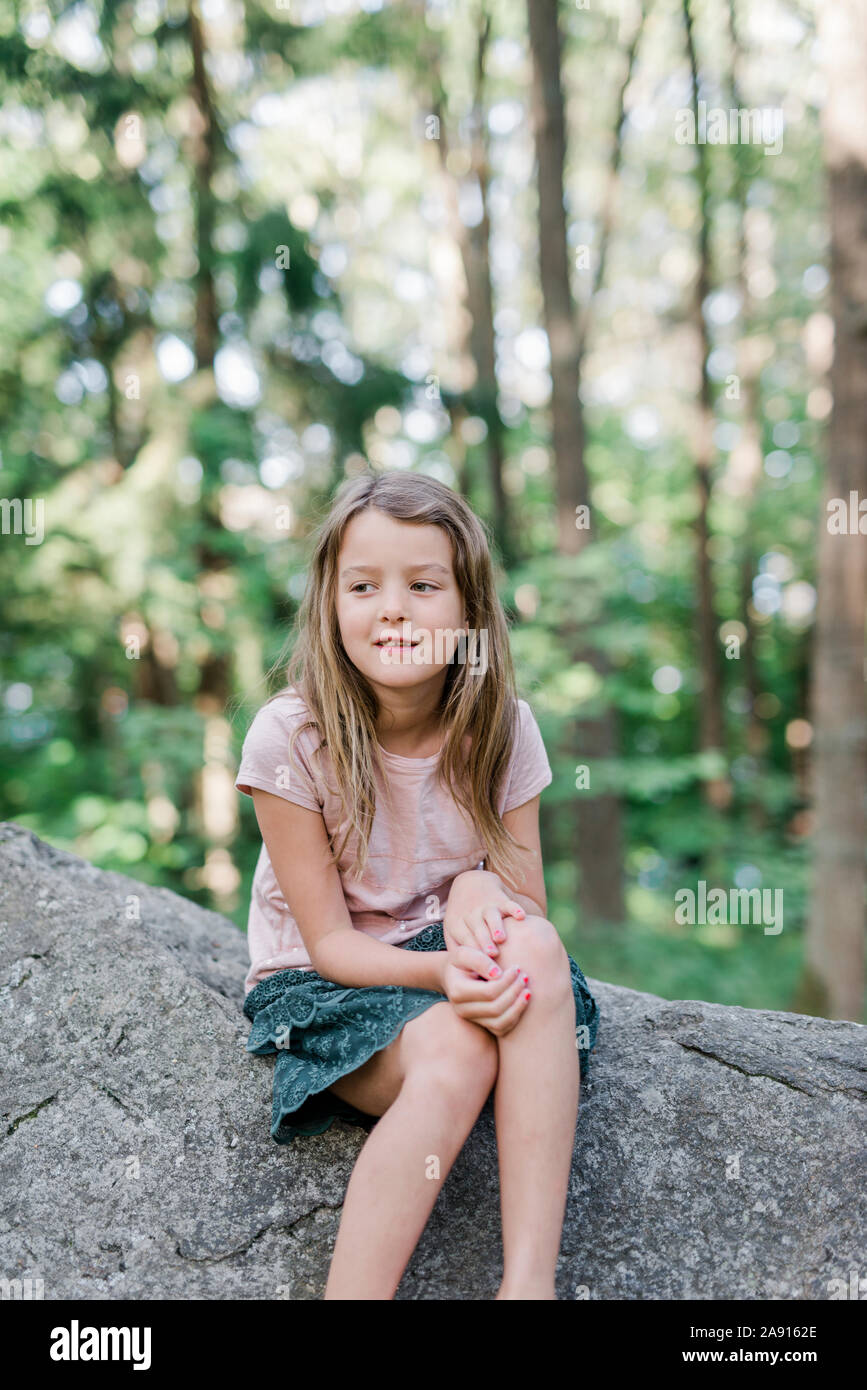 Girl sitting on rock Stock Photo - Alamy