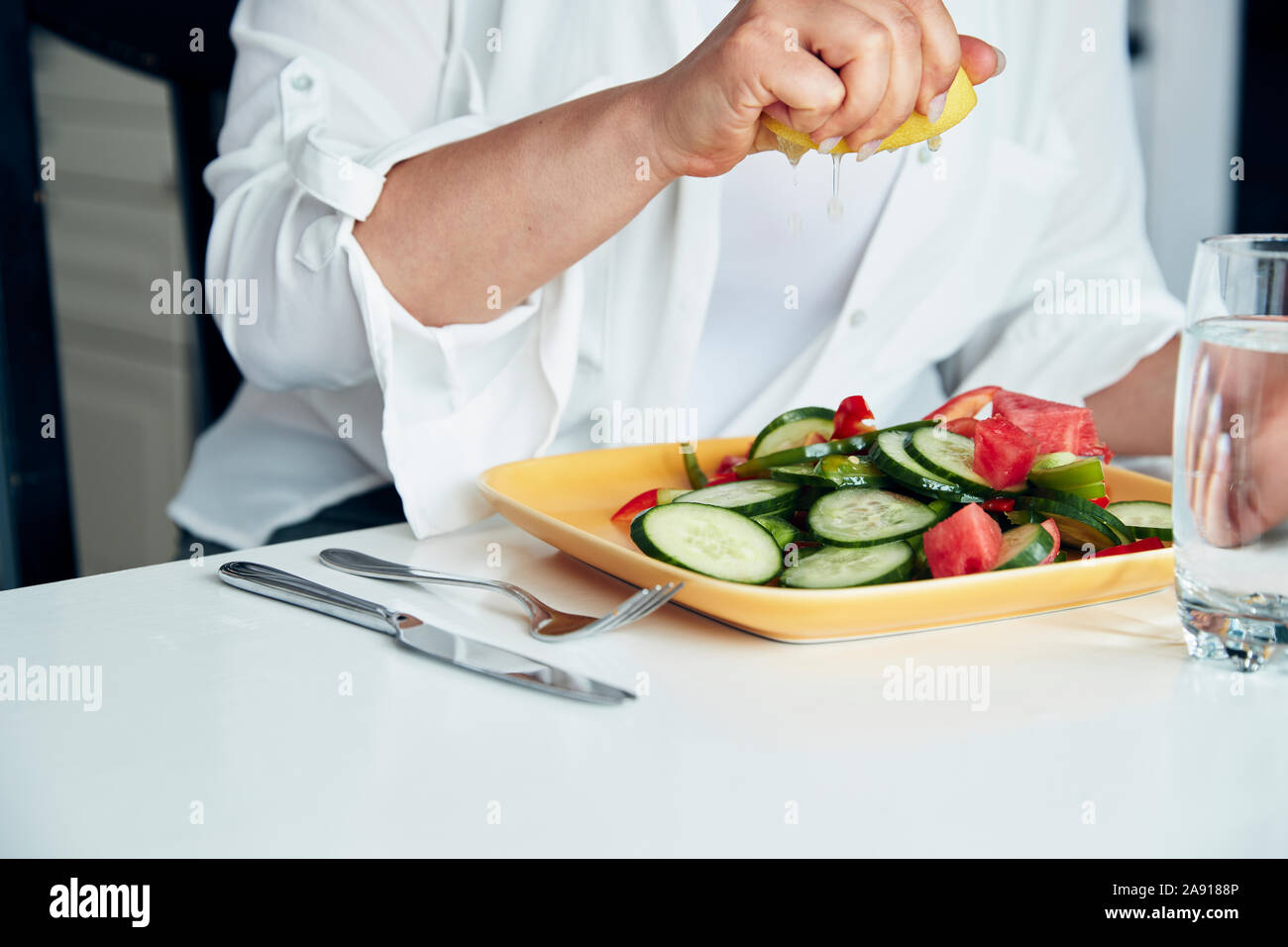Hand squeezing lemon over salad Stock Photo