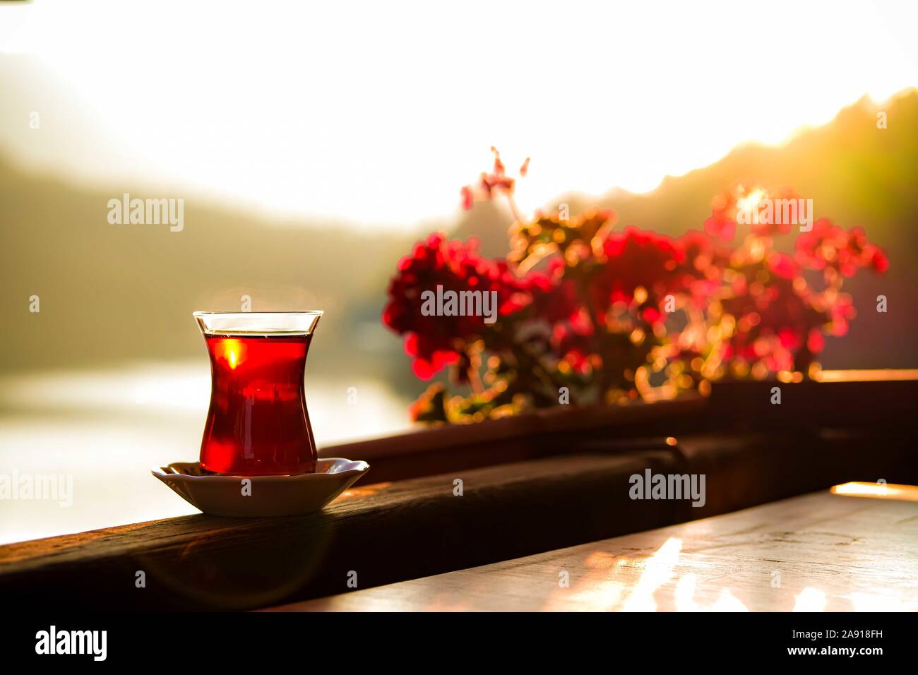 Turkish tea and beautiful sunset at the lake with red flowers background. Lake Golcuk, Bolu, Turkey. Stock Photo