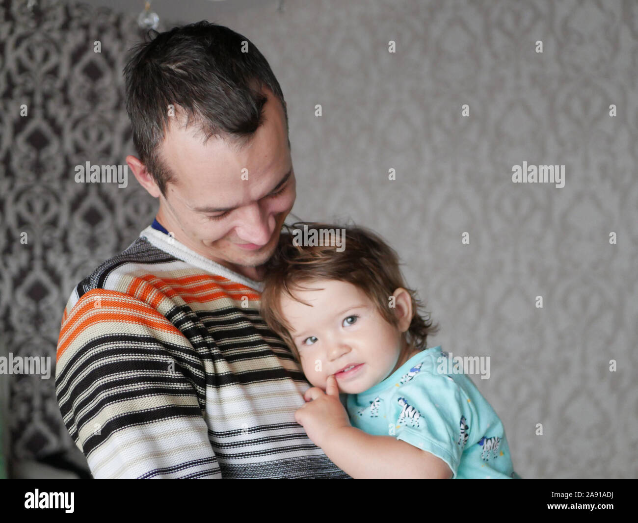 Loving father hugs the child in his arms. Baby 0-1 year old. Fatherly love. The relationship of father and son. A loving father holds a child in his Stock Photo