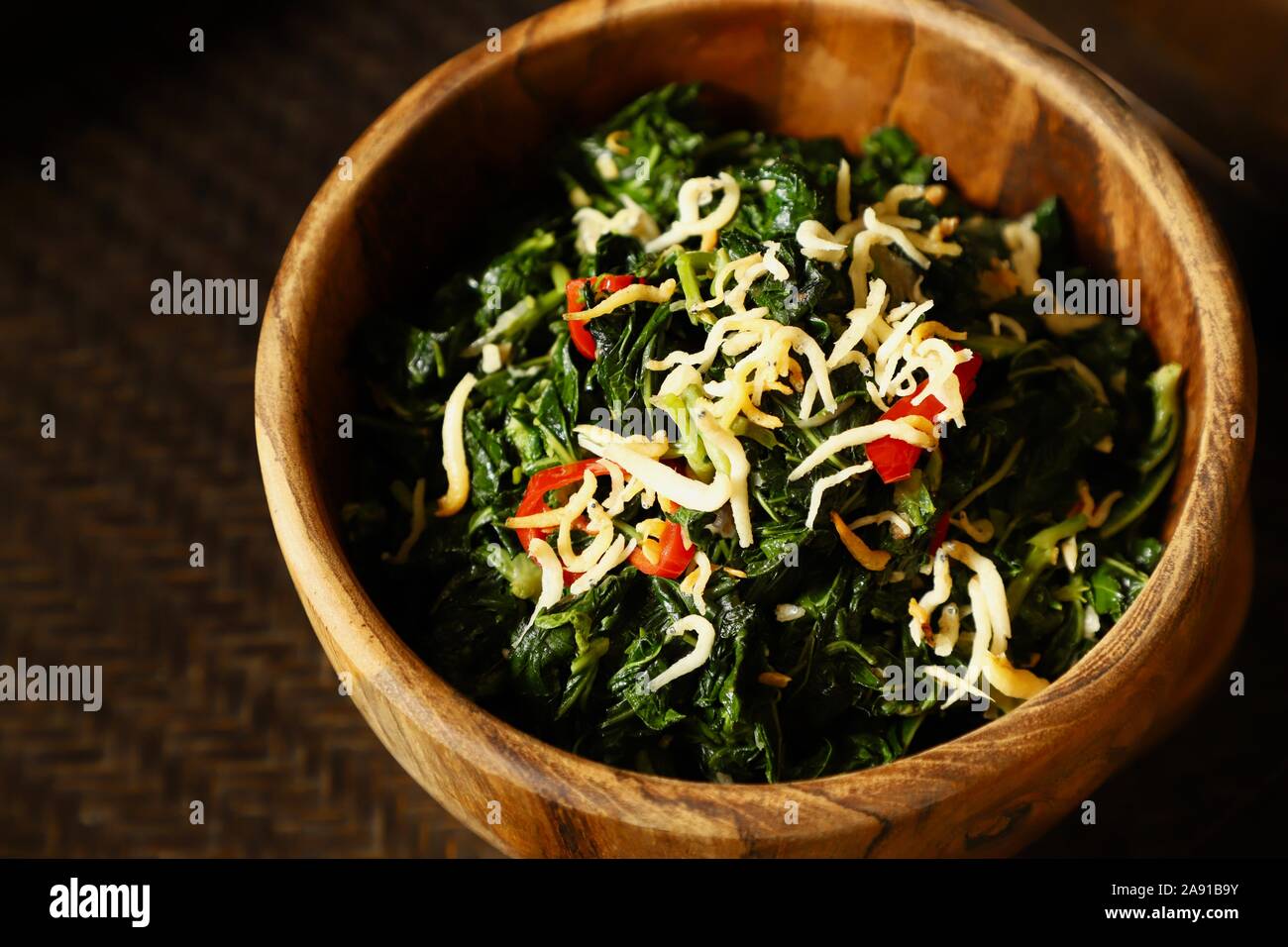 Tumis Daun Singkong. Stir-fried cassava leaf with stinky beans and crispy salte anchovies. Stock Photo