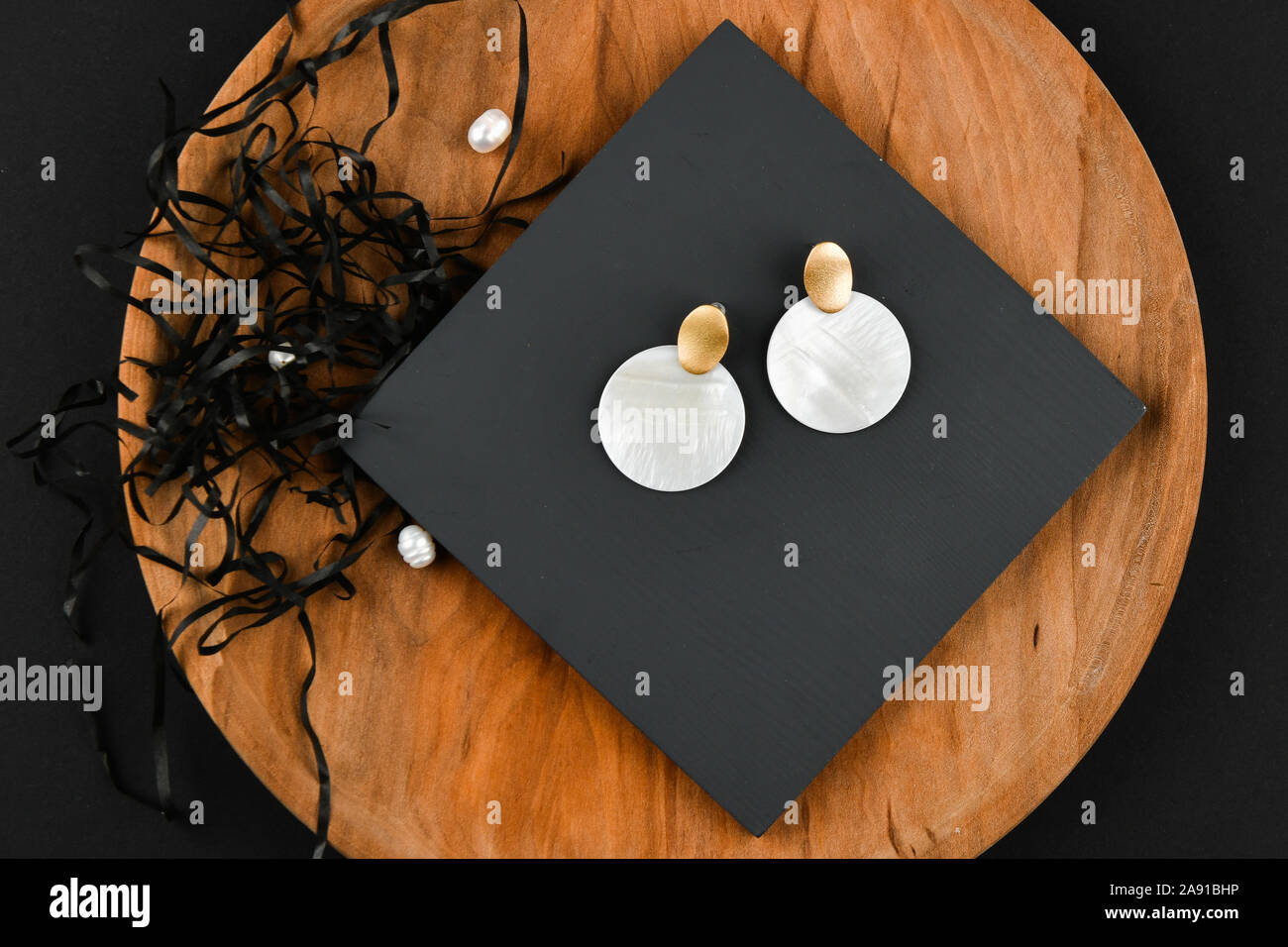 Round white earrings. Close-up. Golden latch. Laid out on a wooden stand. View from above. The concept of jewelry and jewelry. Gifts for women Stock Photo