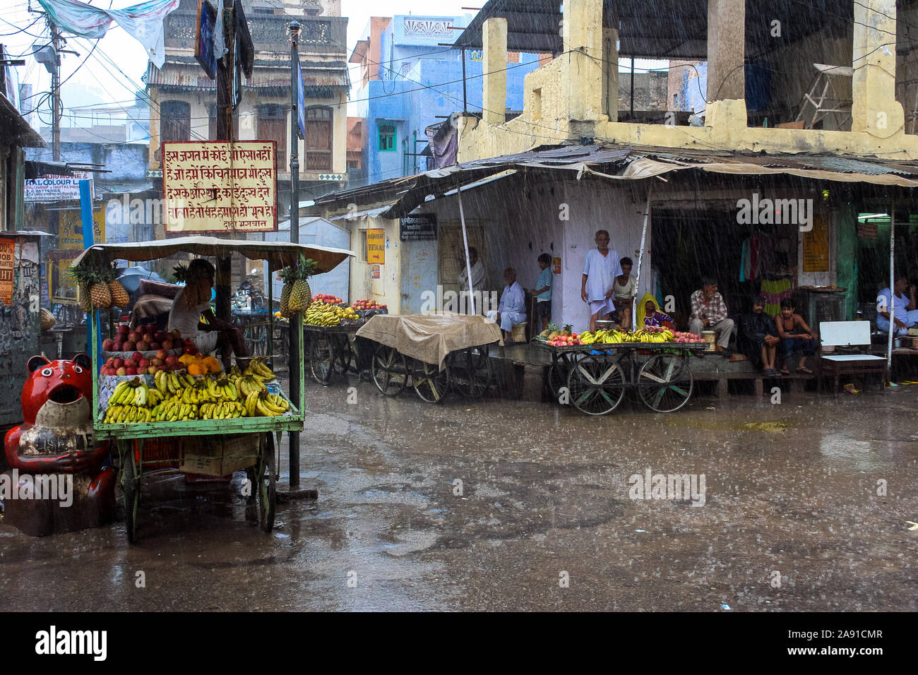 Pushkar, Rajasthan, India: street vendors and shopkeepers shelter from the summer monsoon rain Stock Photo