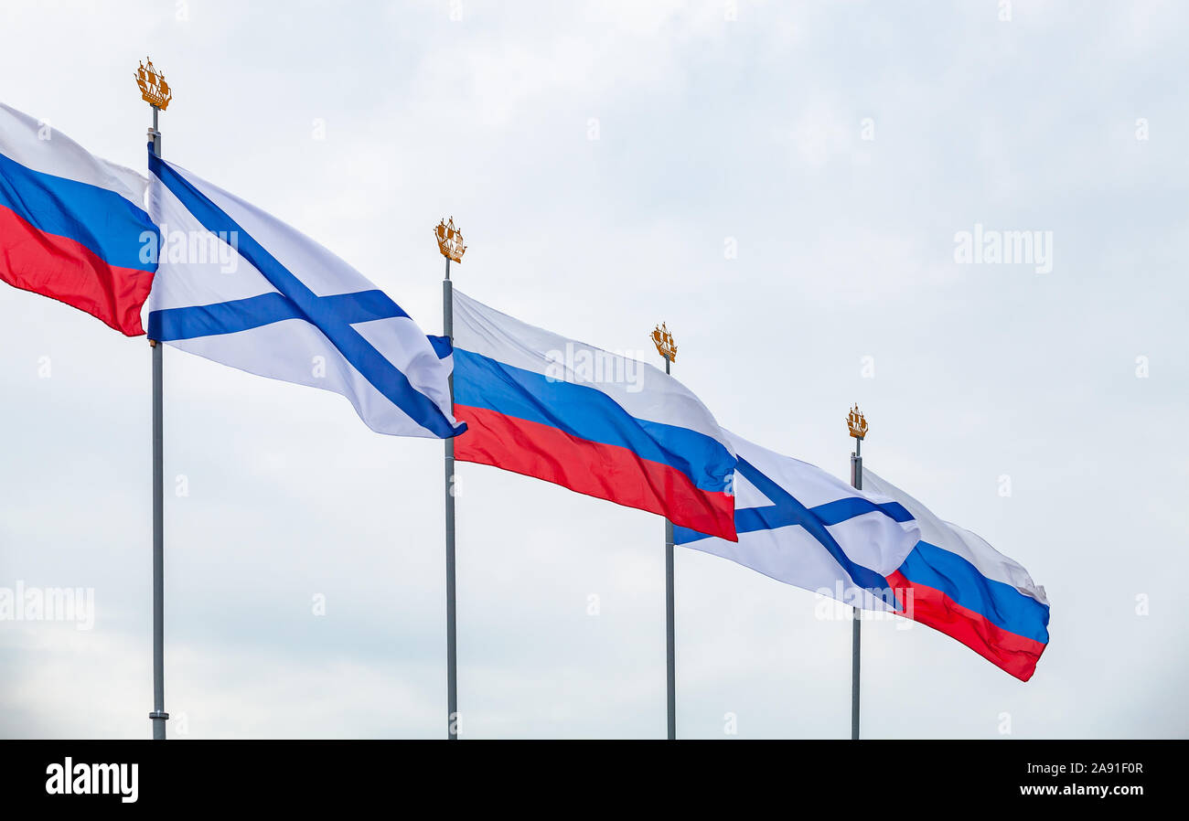 Ensigns of the Russian Navy and Flags of Russia are waving on wind under blue cloudy sky. Military parade decoration, Saint-Petersburg, Russia Stock Photo