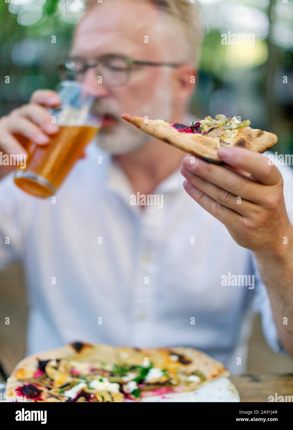 Man eating pizza and drinking a beer Stock Photo