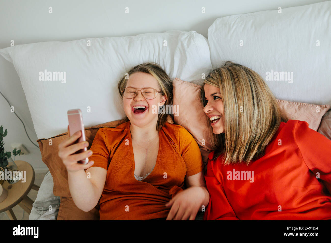 Sisters on bed taking selfie Stock Photo