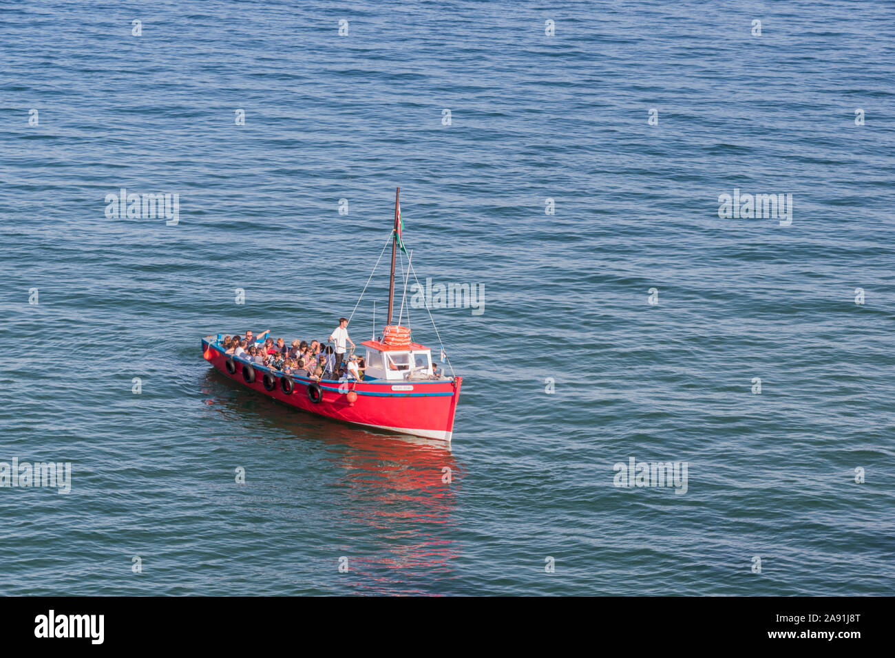 Red ferry boat full of holiday makers comes into port at Tenby, Pembrokeshire. Stock Photo