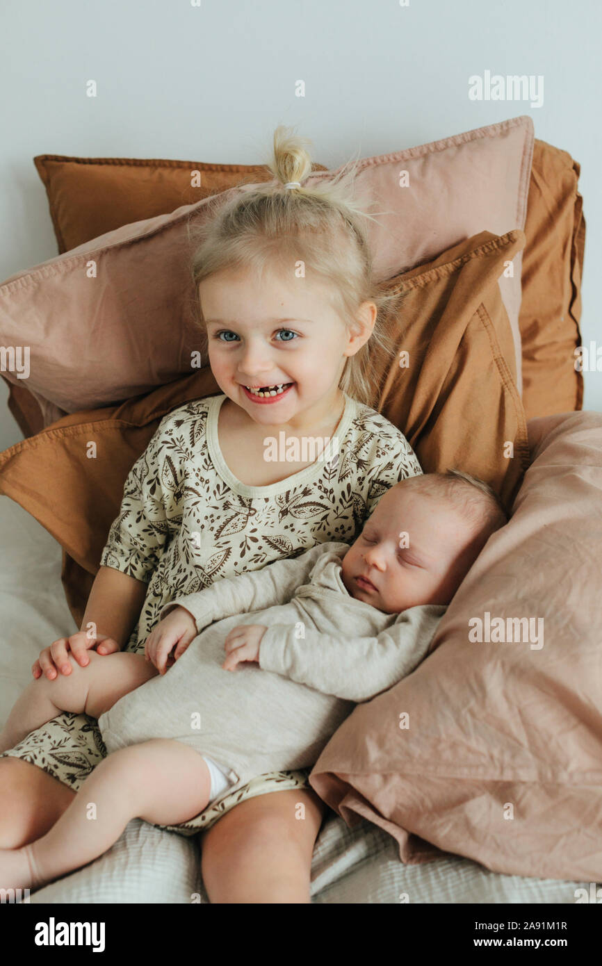 Girl with newborn sibling on bed Stock Photo Alamy