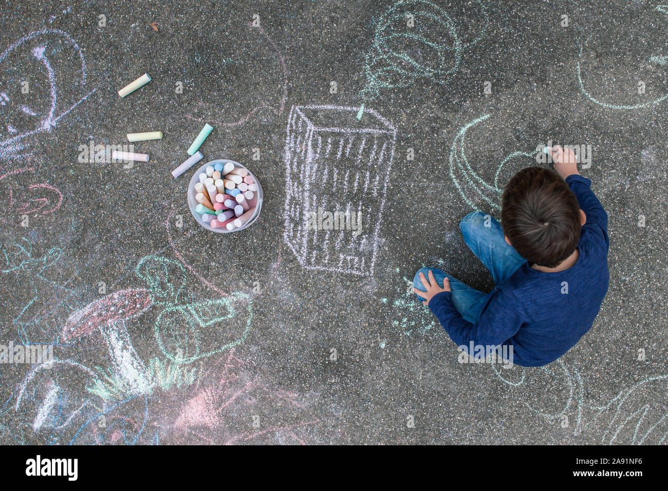 Young boy drawing outside on the sidewalk with chalk Stock Photo - Alamy