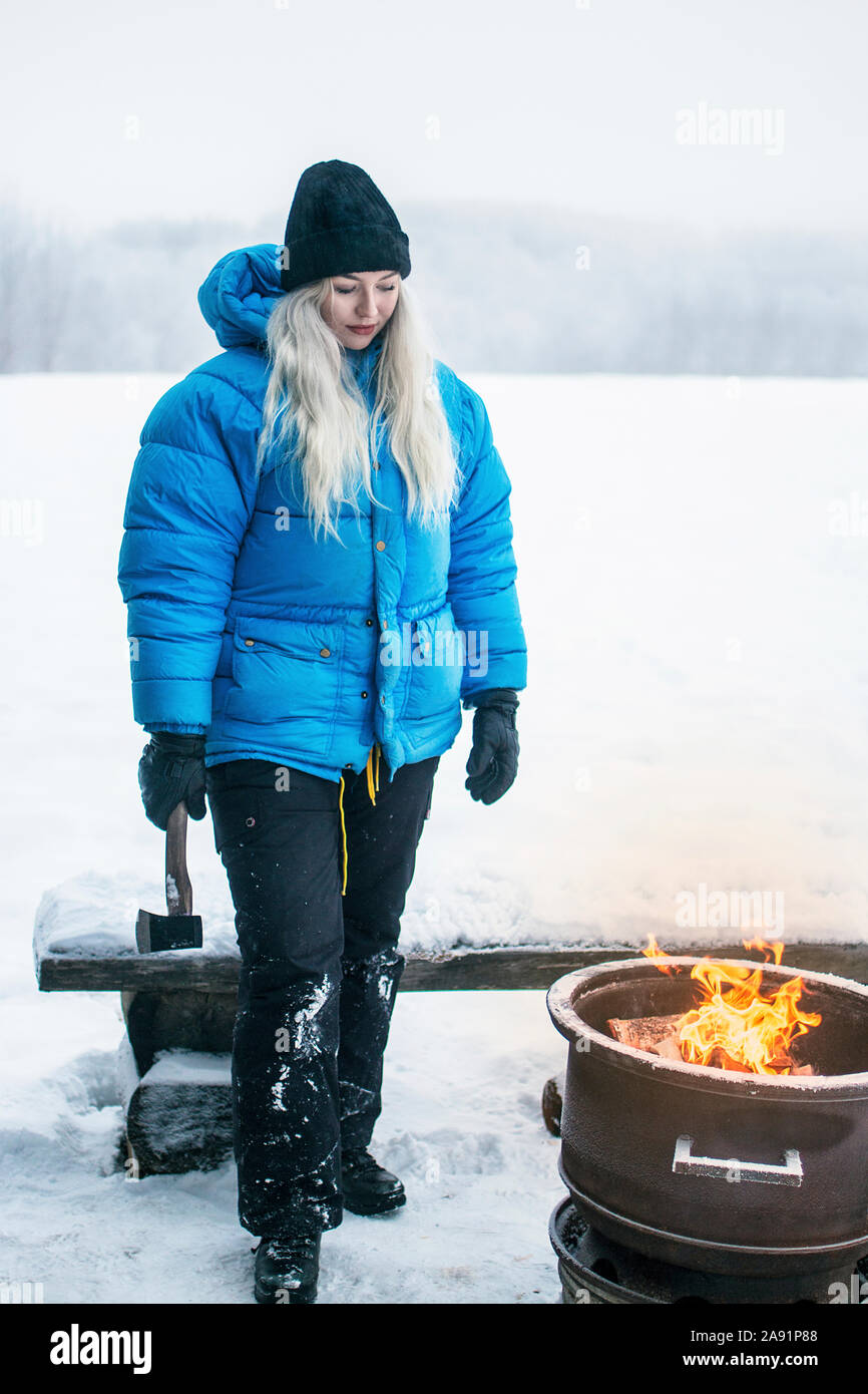 Woman standing with axe at winter Stock Photo