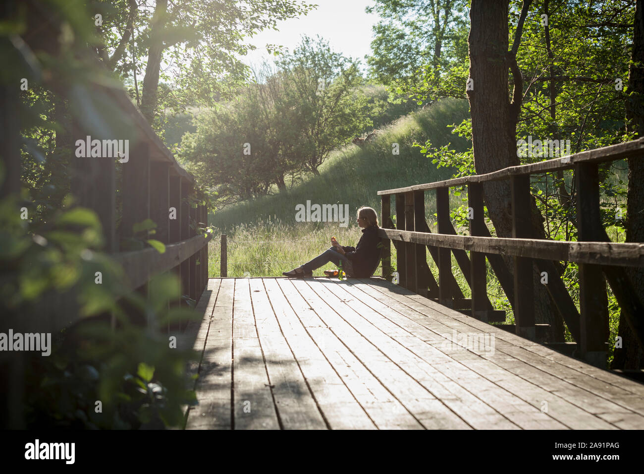 Woman sitting on wooden bridge Stock Photo