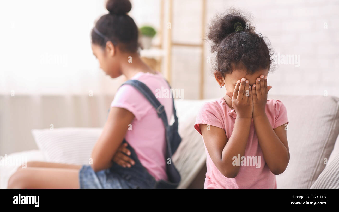 Little african girl crying at home, being ignored by her elder sister Stock Photo
