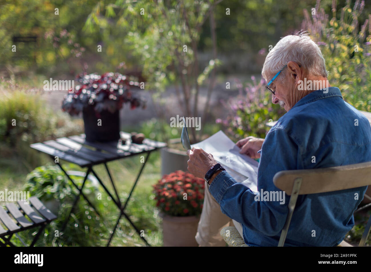 Man in garden reading newspaper Stock Photo