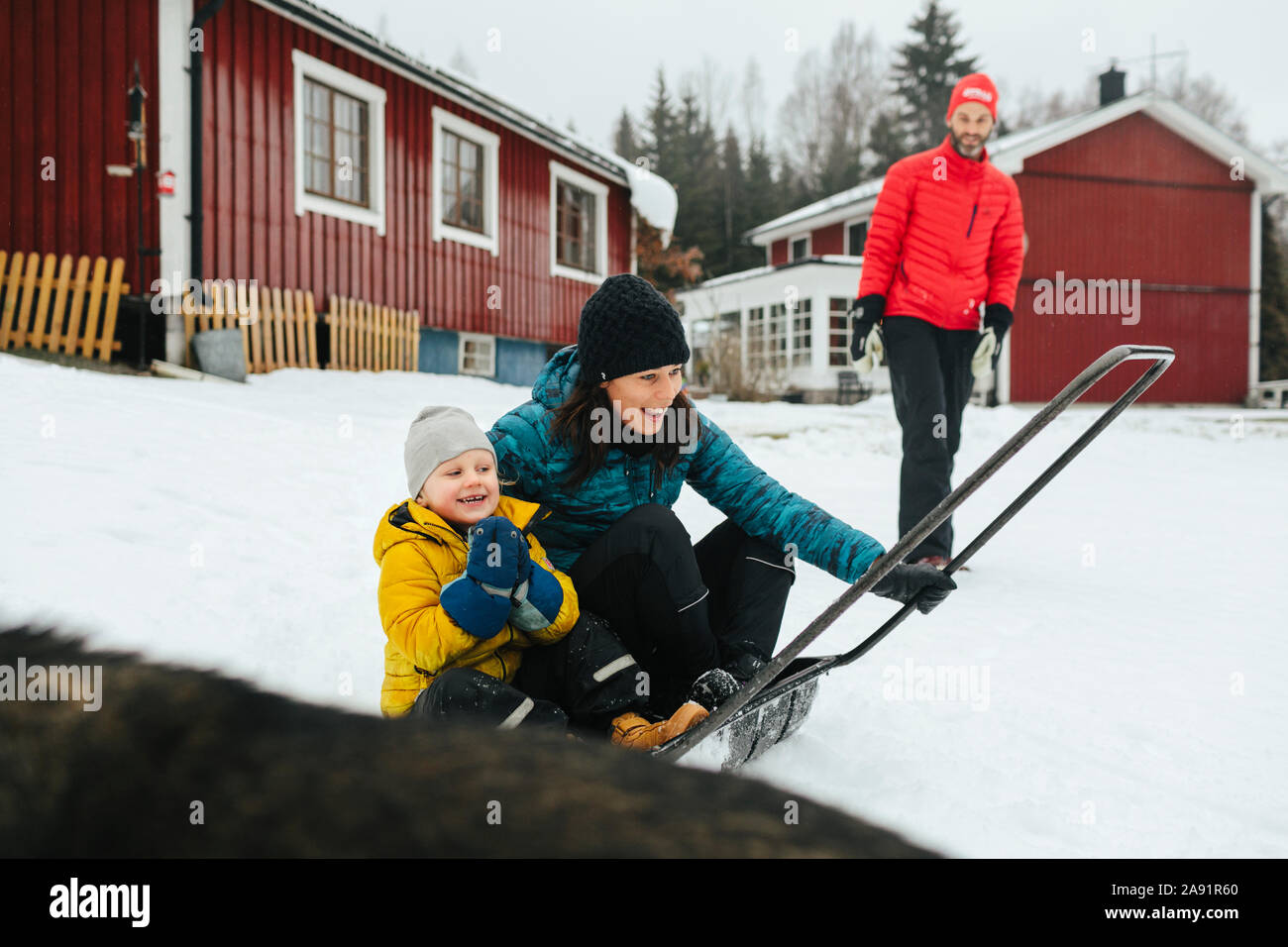 Mother with son on sleigh snow shovel Stock Photo