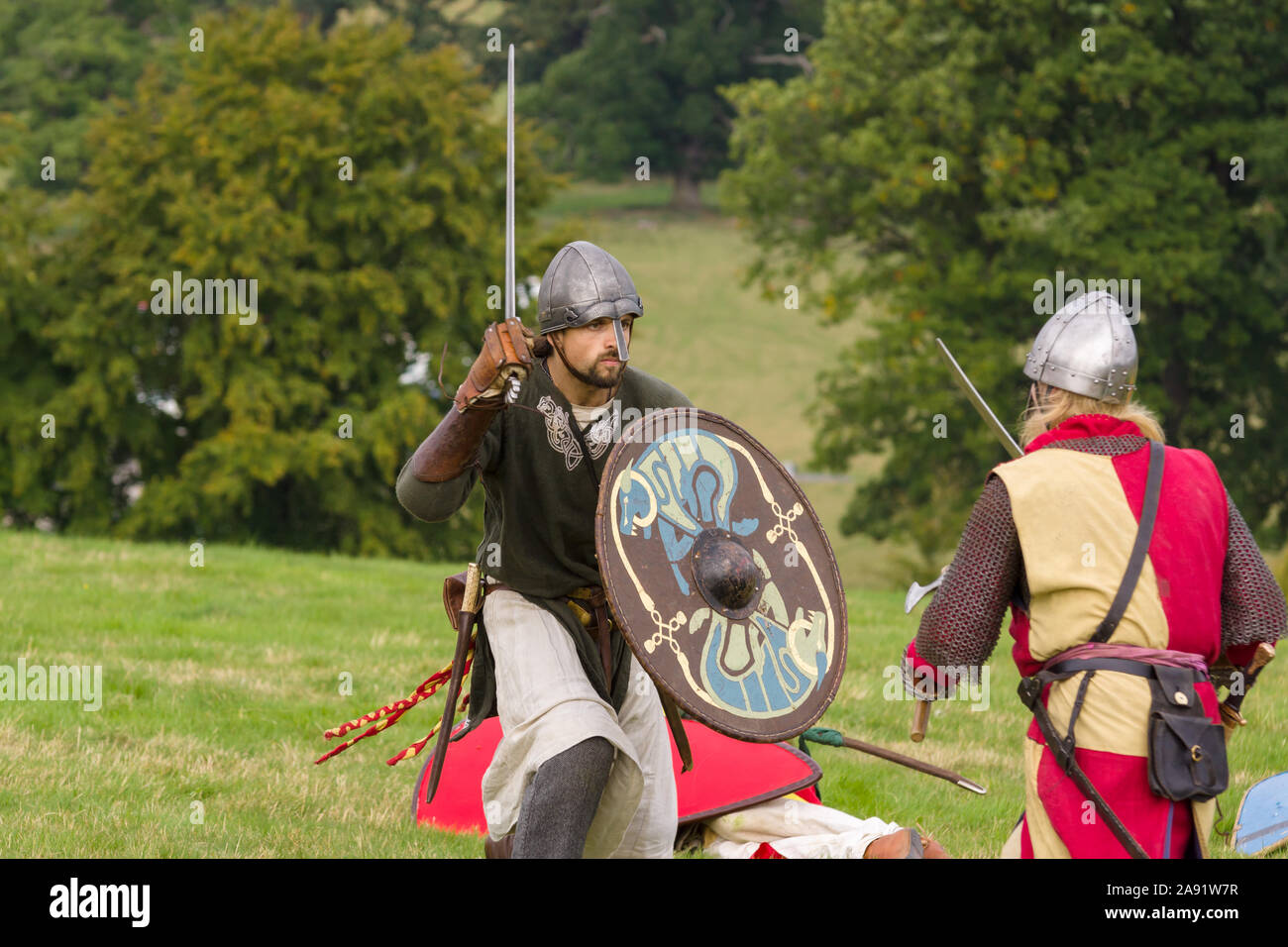 Medieval re-enactors dressed in Welsh and English armour and costumes of the 12th century equipped with weapons simulating combat of the period Stock Photo
