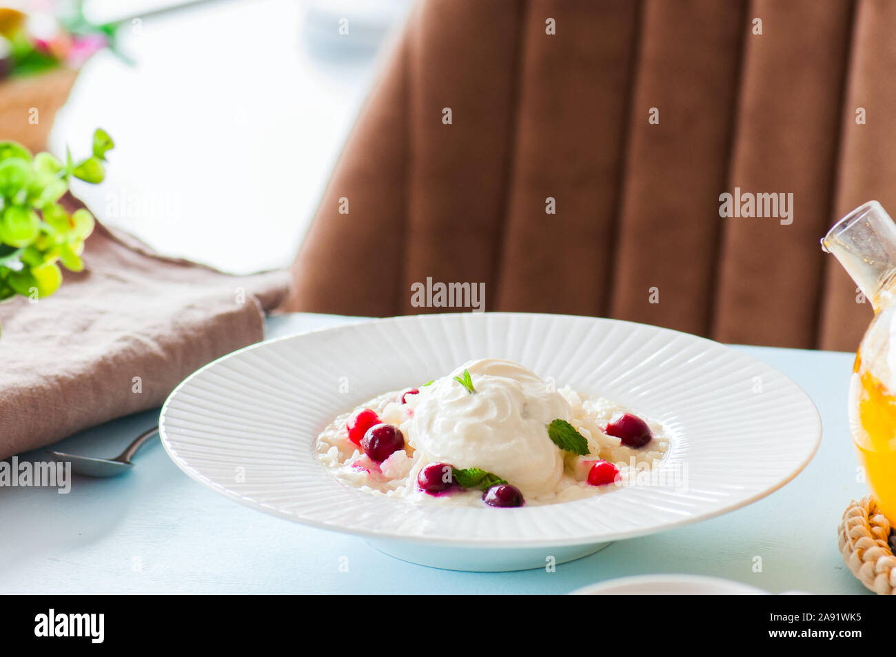 Rice porridge with milk and cranberry in a plate on a table. Breakfast and healthy meal concept. Stock Photo