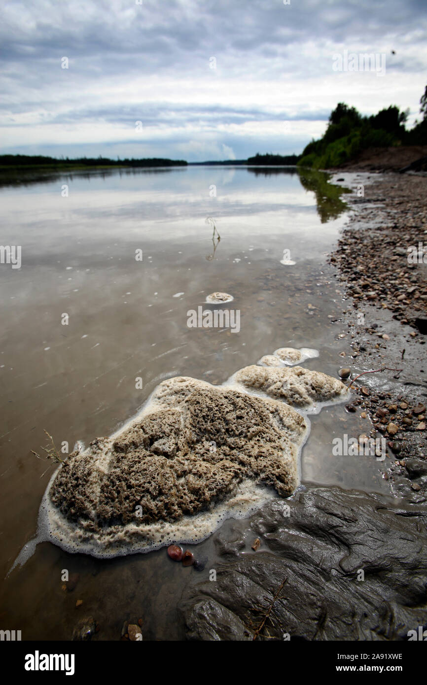Foam on the surface of a river neighboring the tailings ponds used by the oil companies to deposit toxic waste. The Chipewyan band of First Nation that lives in Fort McKay are worried about the environmental impact of allowing the oil sand companies to operate in their neighborhood. Stock Photo