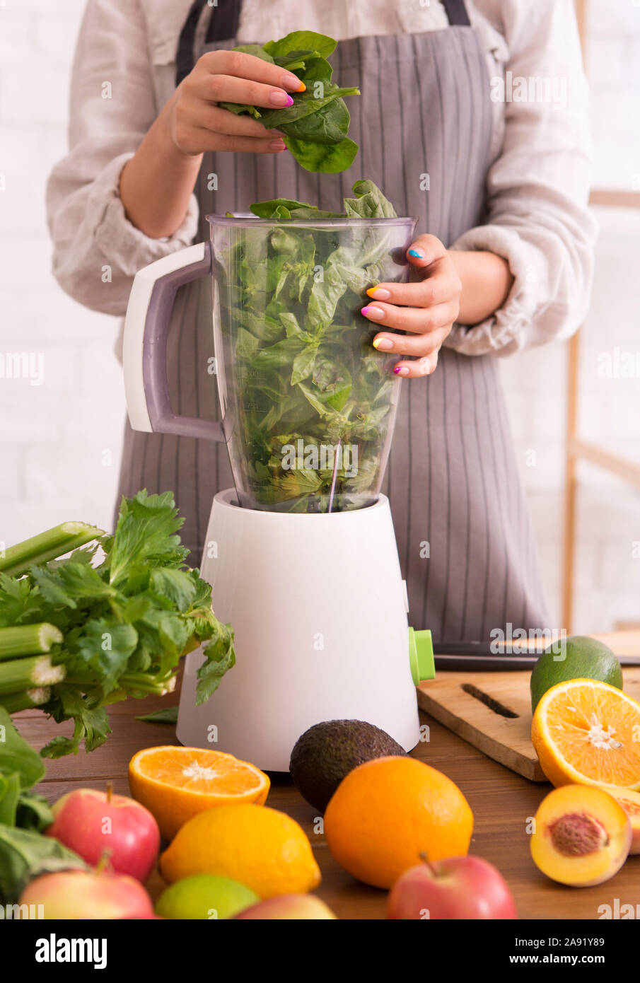 Woman mixing fresh fruits and vegetables in blender for cooking healthy