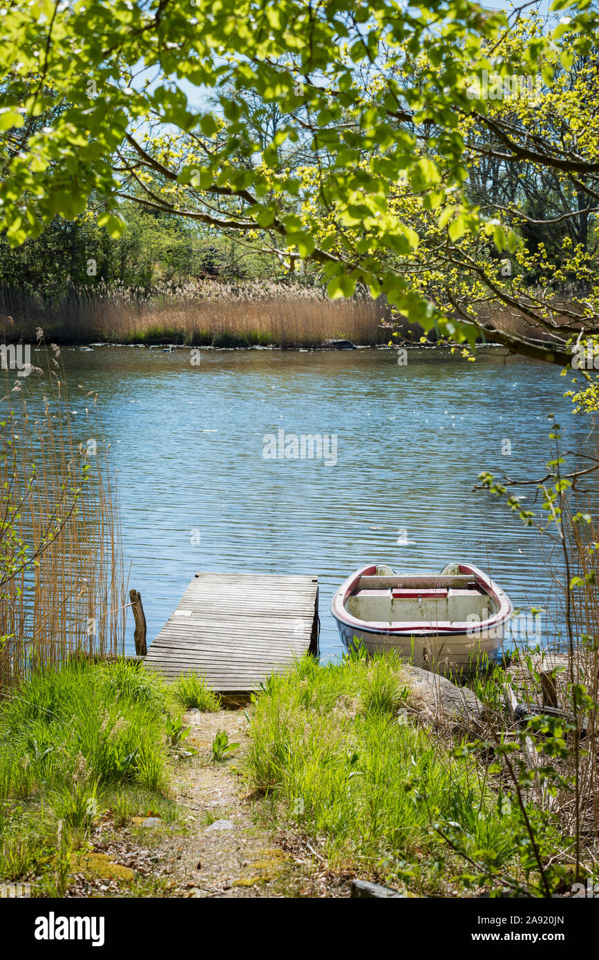 View of lake with jetty and rowing boat Stock Photo