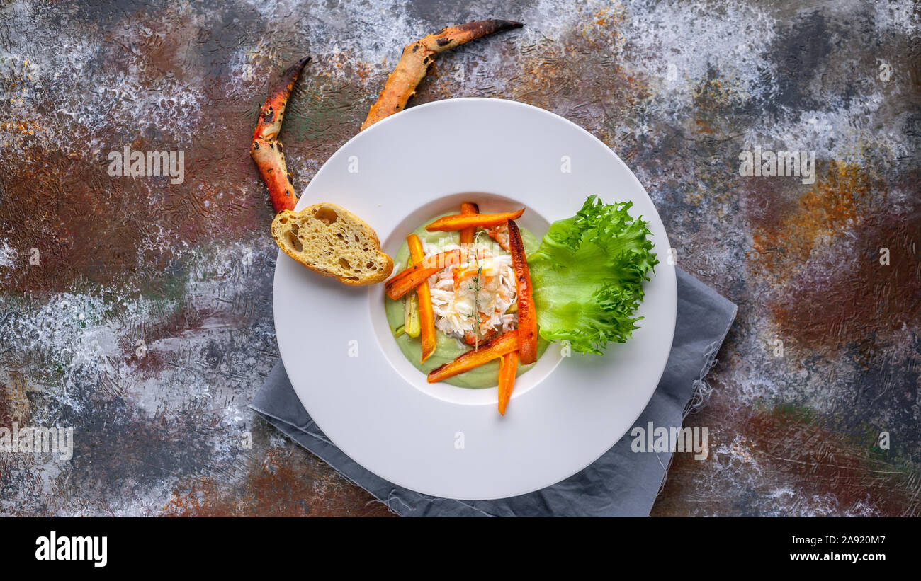 Food web banner. Close-up salad with snow crab meat, avocado and vegetables. Serving on a gray napkin and a rusty background Stock Photo