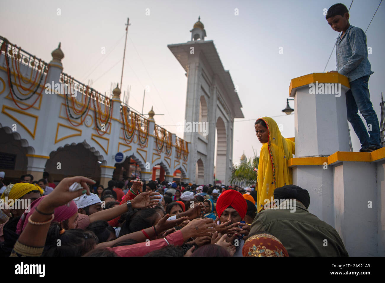 Visitors reach for food at the Gurudwara Bangla Sahib Temple in New Delhi, India, as people begin to celebrate the Guru Nanak Jayanti Festival. The Prince of Wales will visit the country this week. Stock Photo