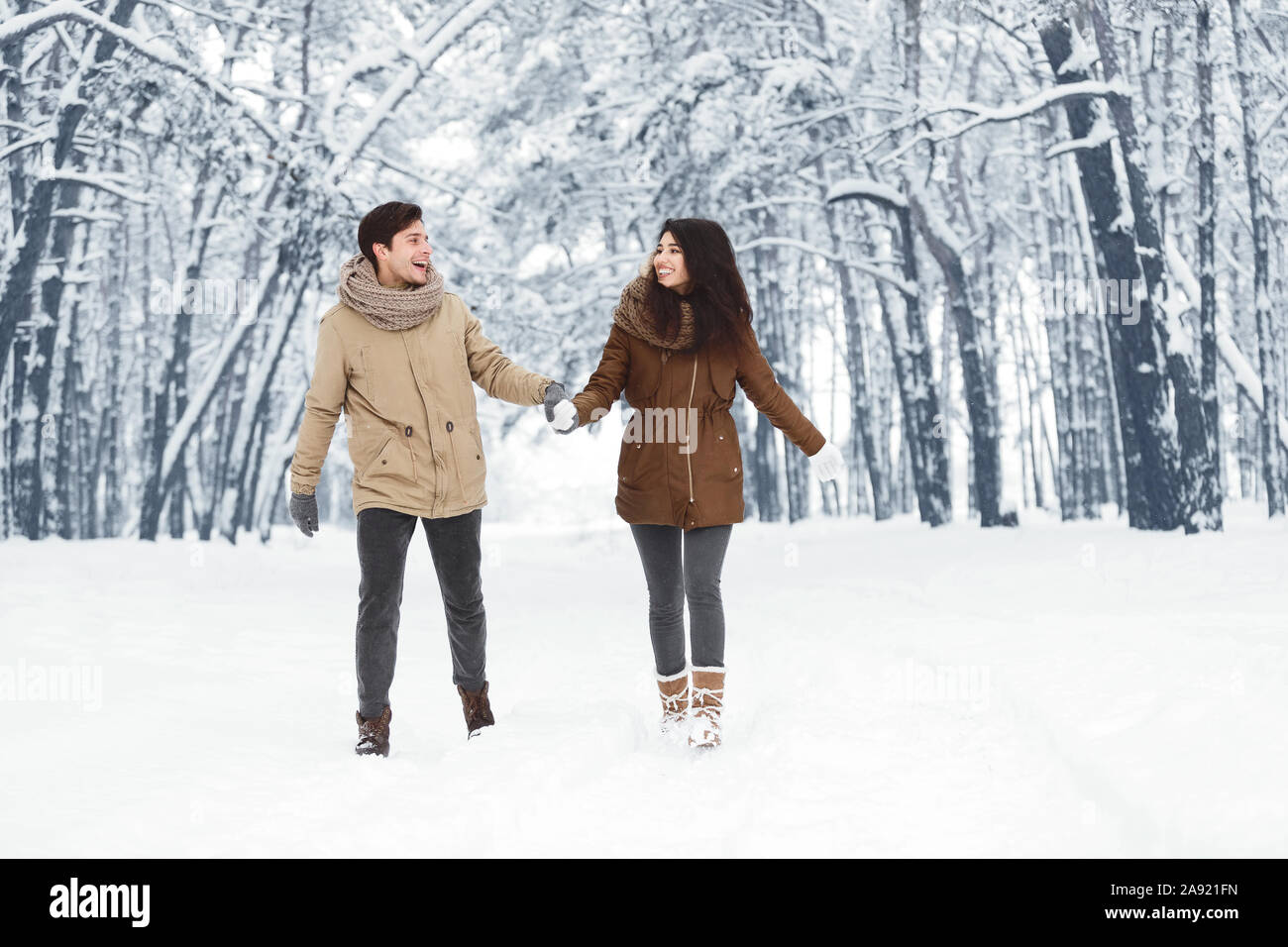 Happy Couple Walking Holding Hands Through Snowy Forest Stock Photo - Alamy