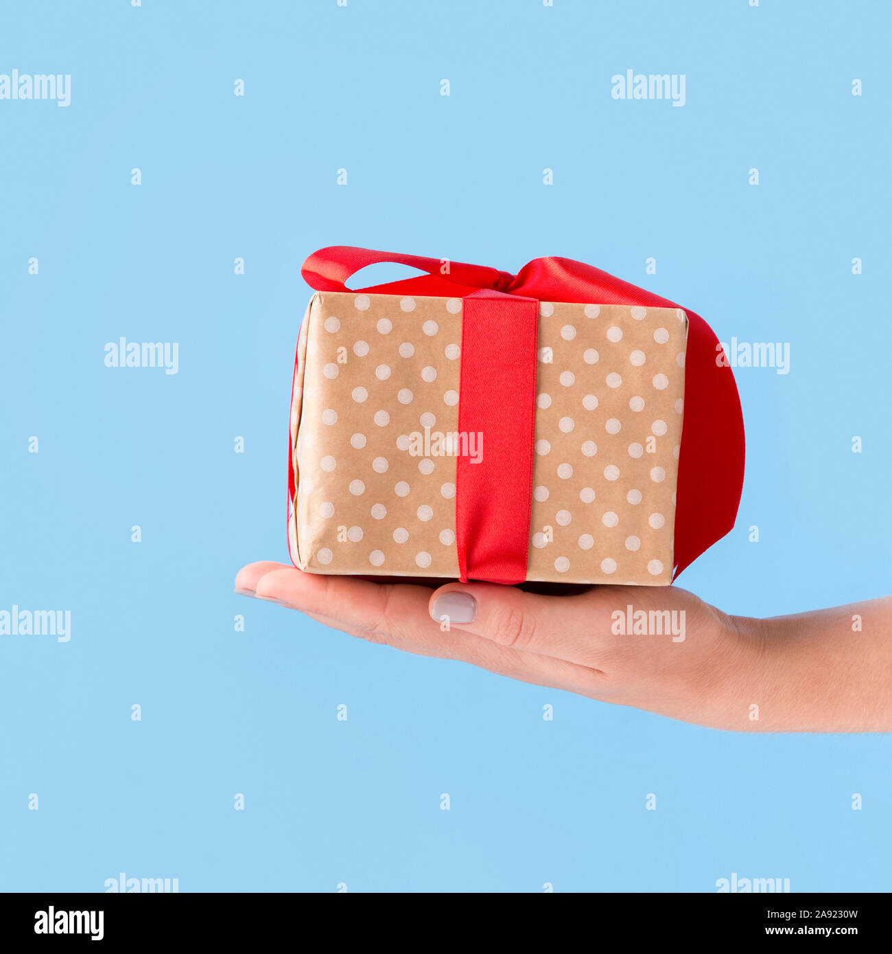 Small Christmas present in box wrapped in bow over blue Stock Photo