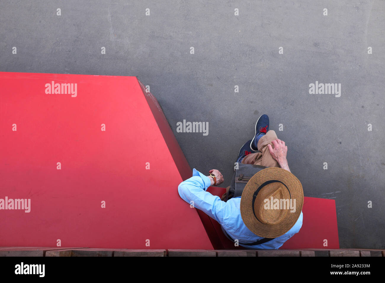 Man wearing a hat, seen from above, sitting alongside an installation on the Pont Boieldieu, Rouen, Normandy, France Stock Photo