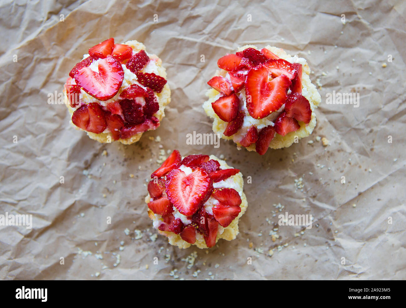 Very tasty muffins with fresh strawberries lie on kraft paper. Stock Photo