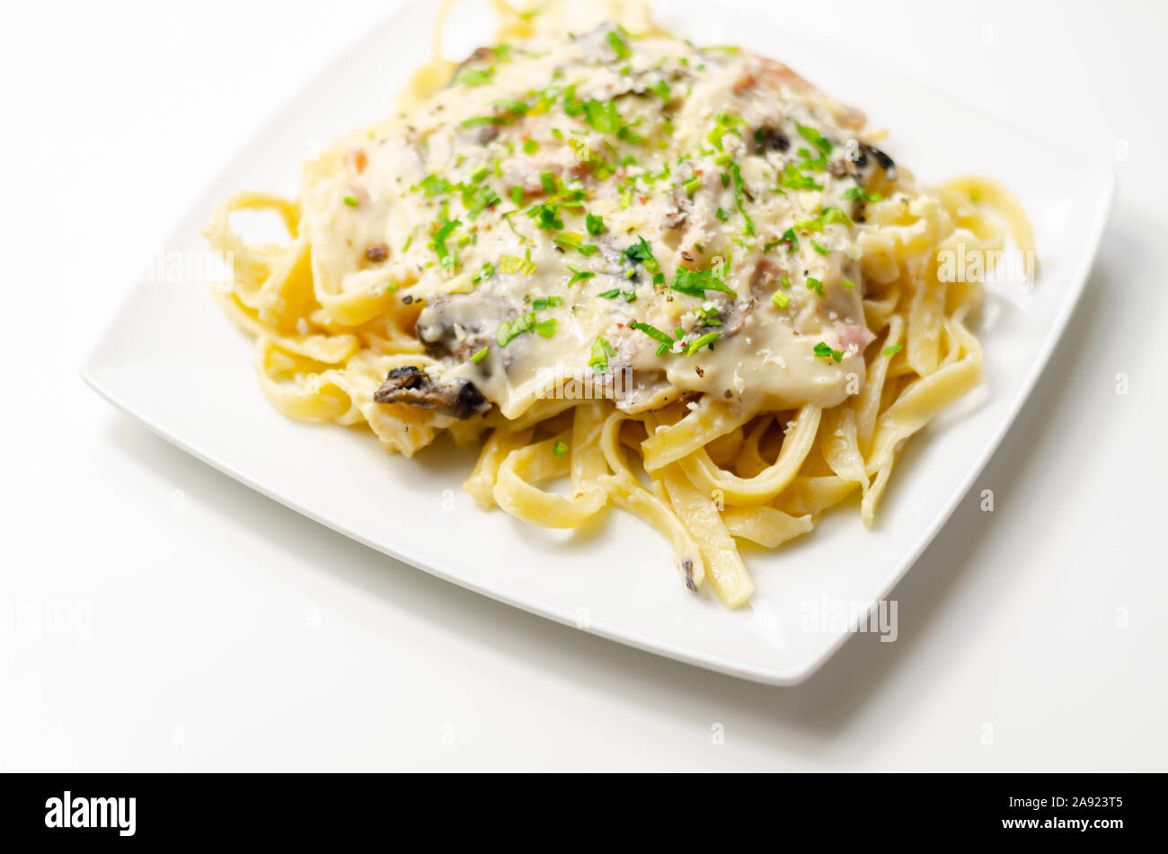 Tagliatelle pasta with smoked pulled ham hock and roasted mushrooms in a cheese sauce, italian food Stock Photo