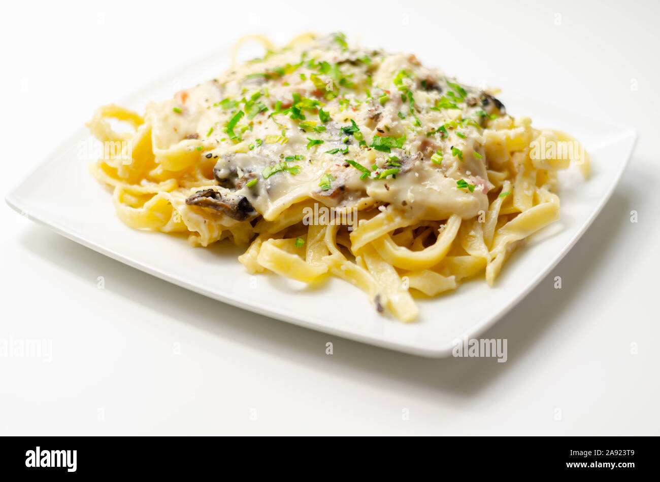 Tagliatelle pasta with smoked pulled ham hock and roasted mushrooms in a cheese sauce, italian food Stock Photo