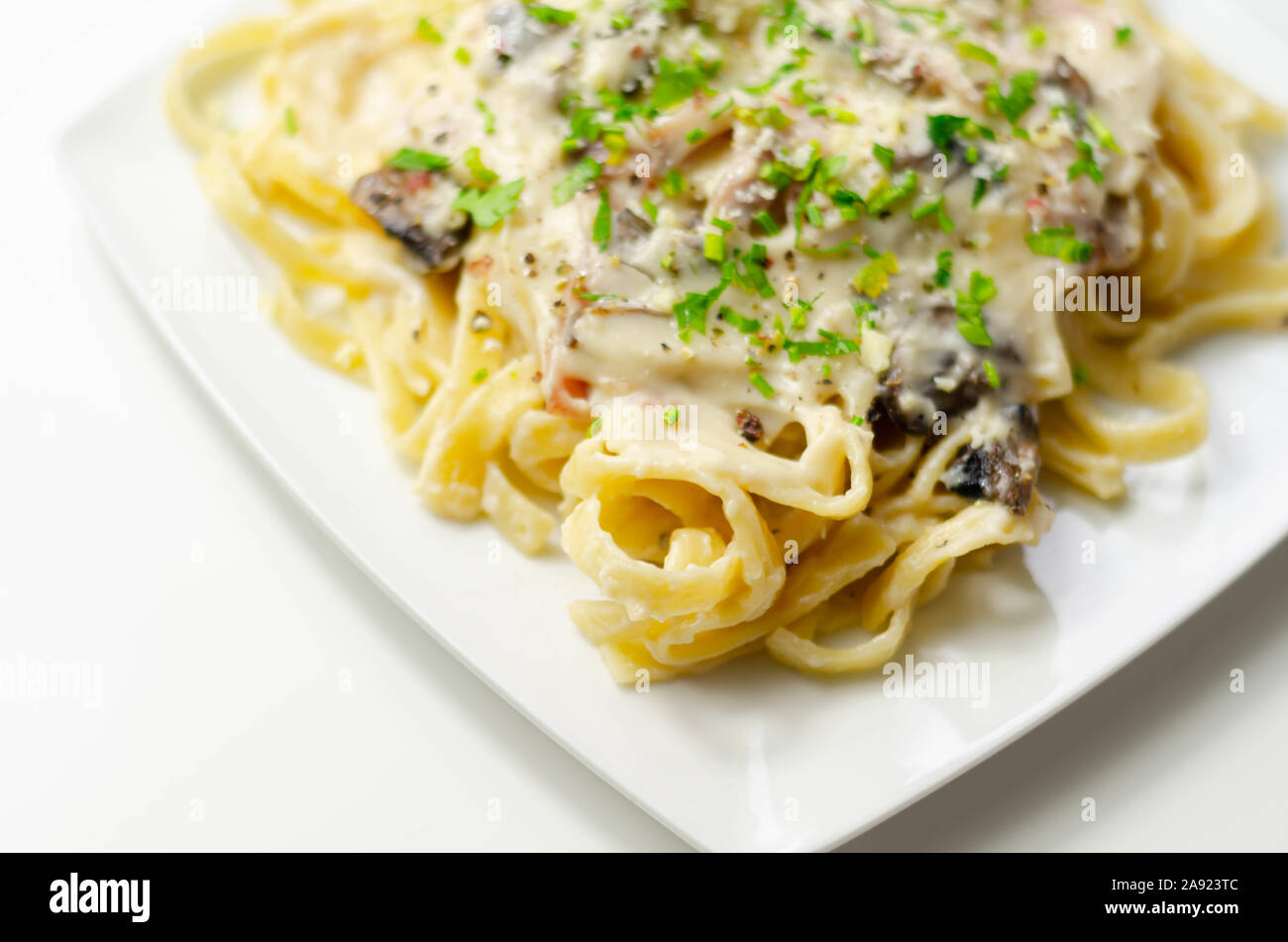 Tagliatelle pasta with smoked pulled ham hock and roasted mushrooms in a cheese sauce, italian food Stock Photo