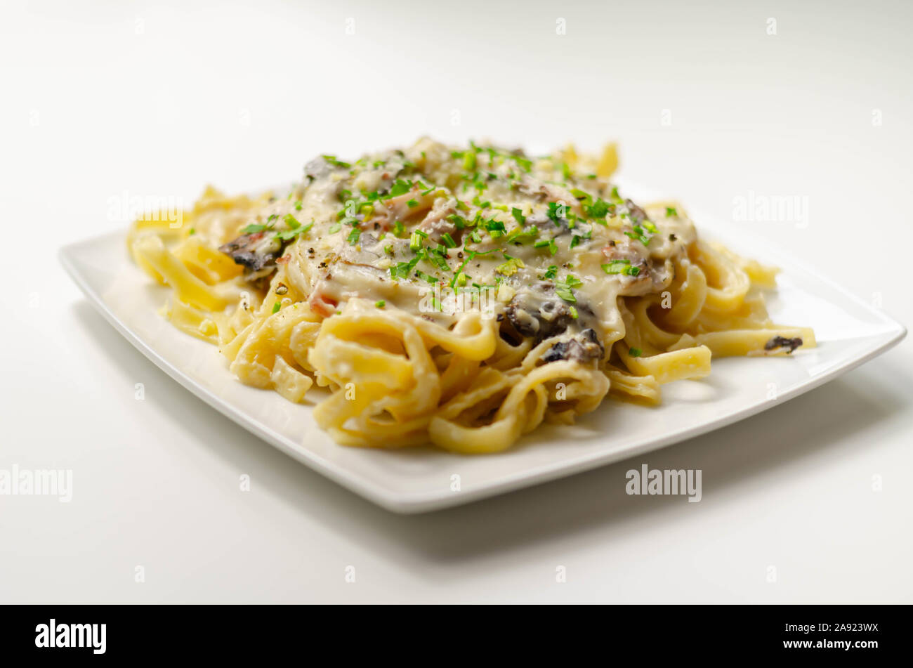 Tagliatelle pasta with smoked pulled ham hock and roasted mushrooms in a cheese sauce, italian food Stock Photo