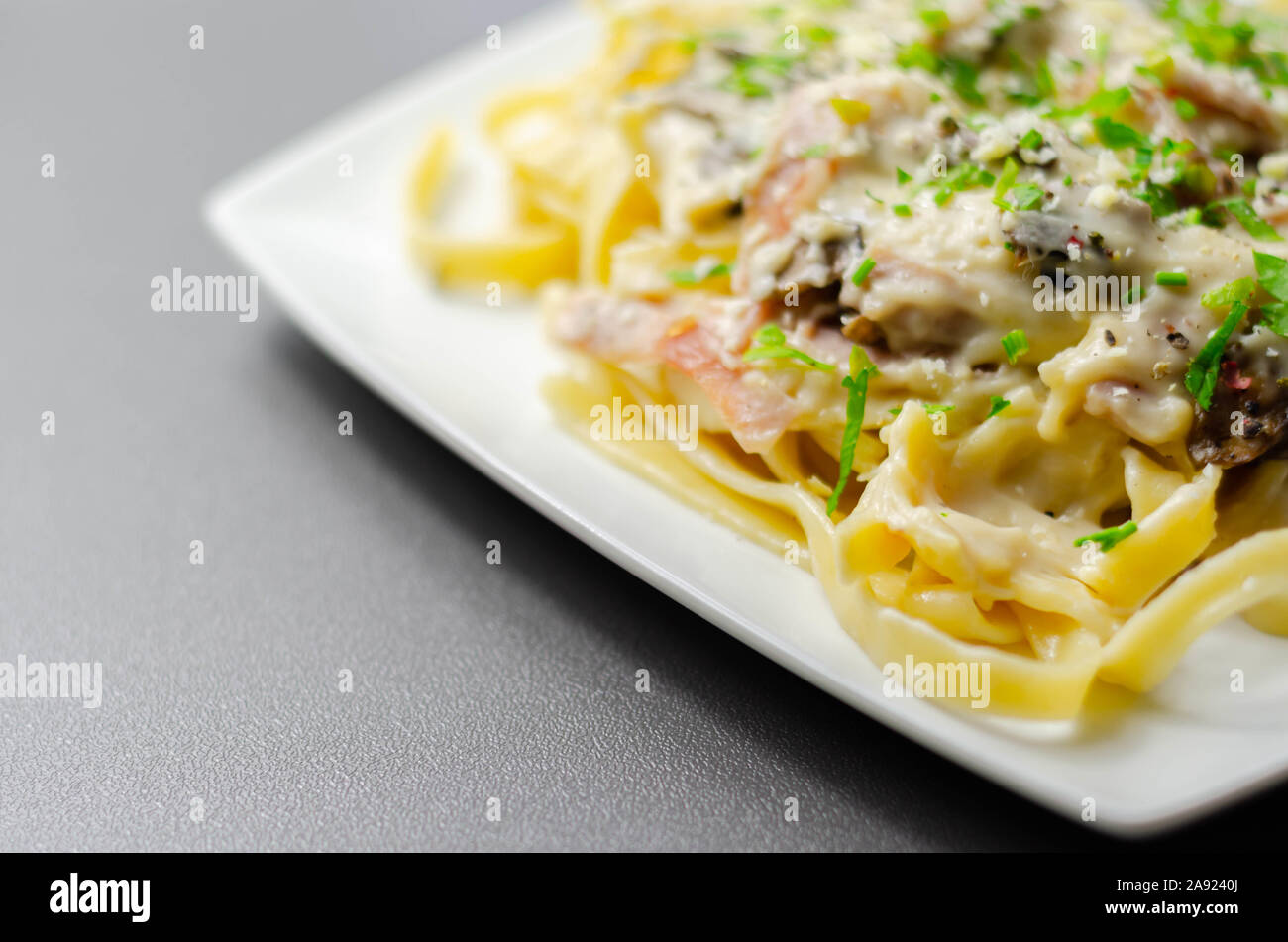 Tagliatelle pasta with smoked pulled ham hock and roasted mushrooms in a cheese sauce, italian food Stock Photo