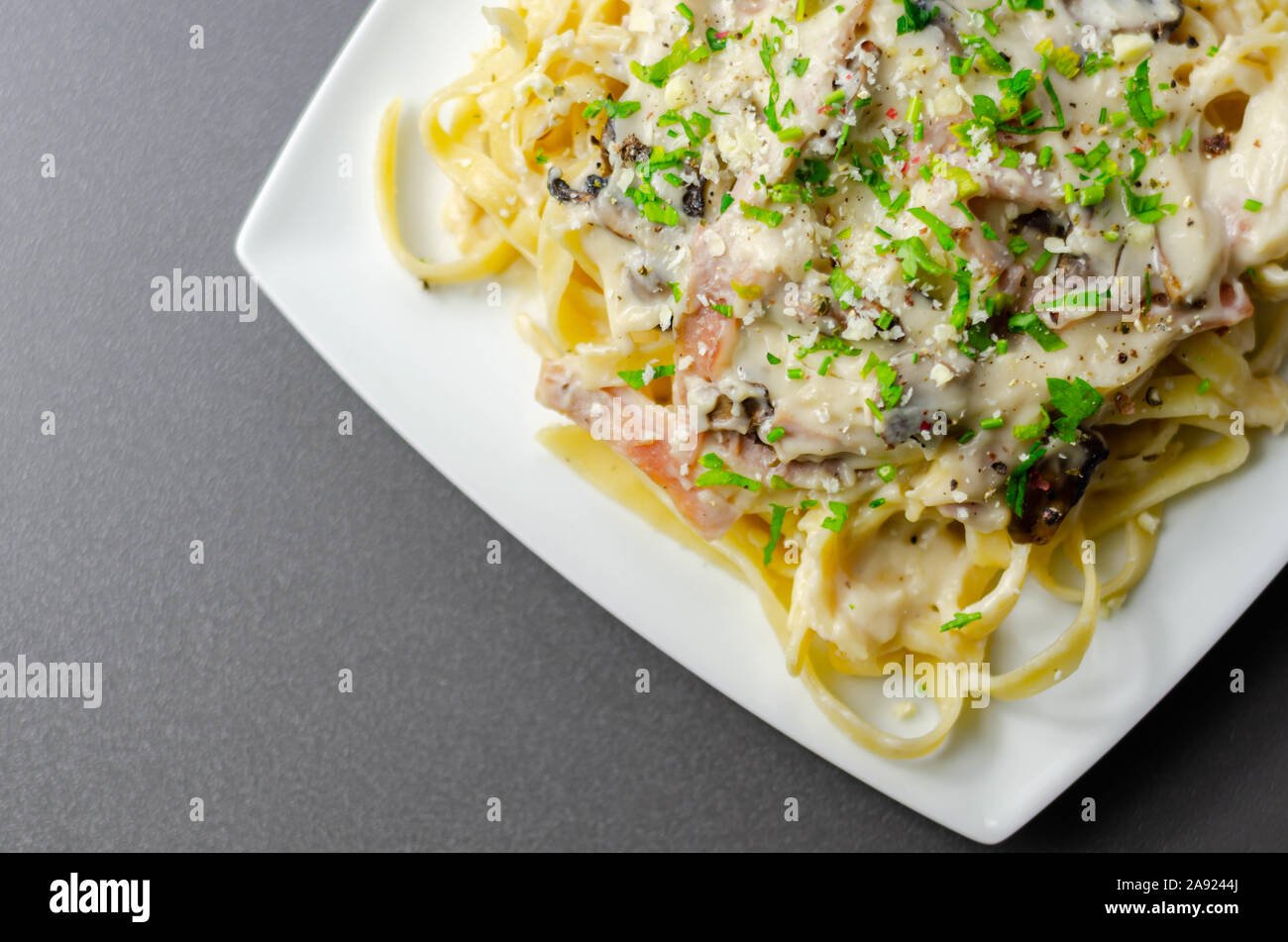 Tagliatelle pasta with smoked pulled ham hock and roasted mushrooms in a cheese sauce, italian food Stock Photo