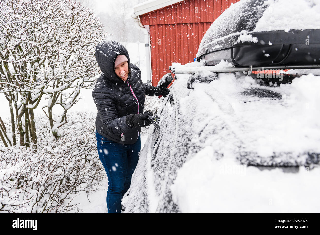 Woman clearing snow from car Stock Photo