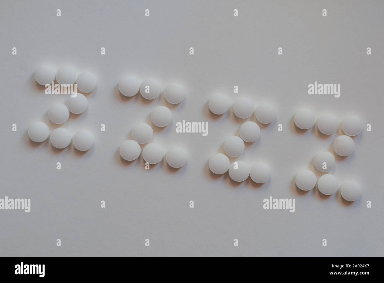 white pills spelling out ZZZZ on white background .concept insomnia ,Melatonin to help sleep..room for text. Stock Photo