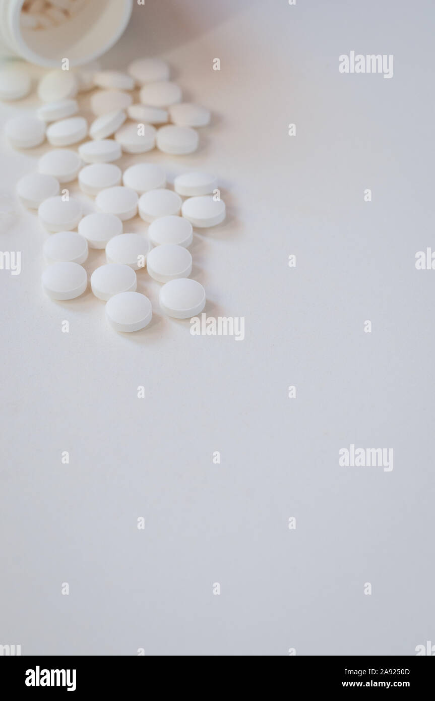 white pills on white background spilling out of bottle,Melatonin to help sleep.room for text. Stock Photo