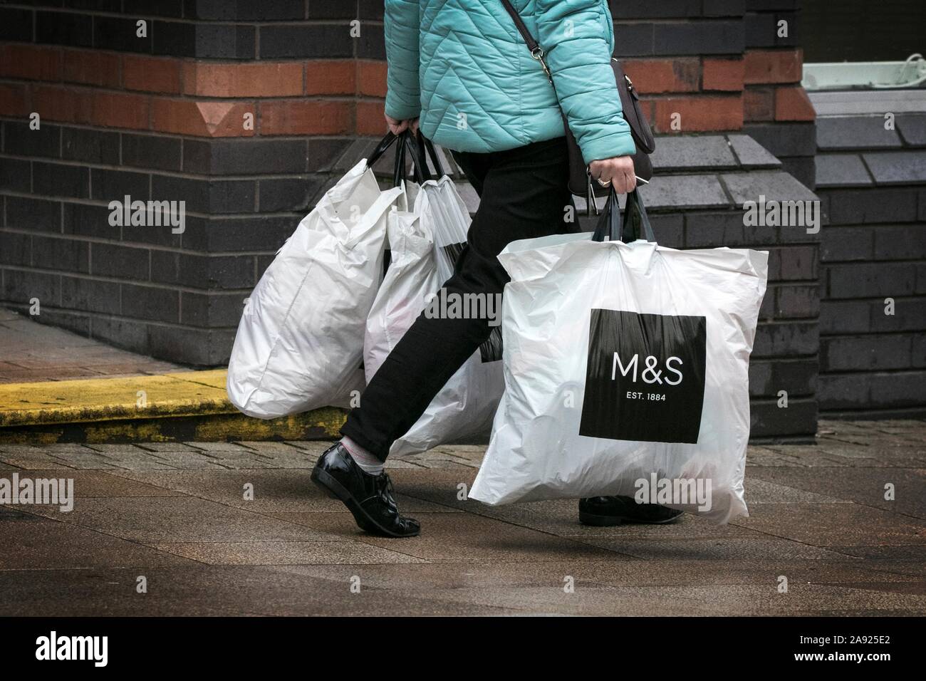 A woman carrying M & S Marks and Spencer clothing store plastic carrier ...